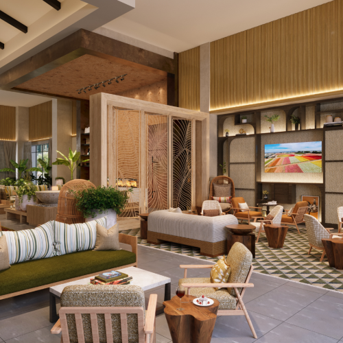 A modern hotel lobby with warm wood tones, comfortable seating, large plants, pendant lighting, a fireplace feature, and a wall-mounted TV displaying colorful art.