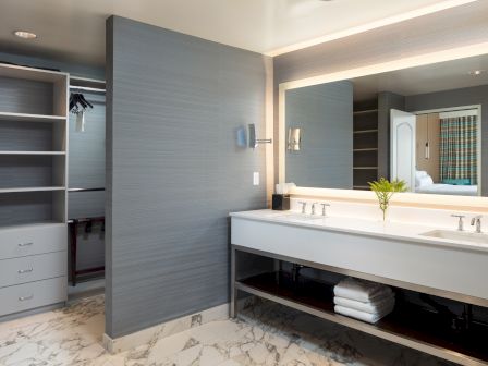 A modern bathroom with a double sink vanity, large mirror, gray walls, open shelving, and a marble floor. Top it at 140 characters, always ending the sentence.