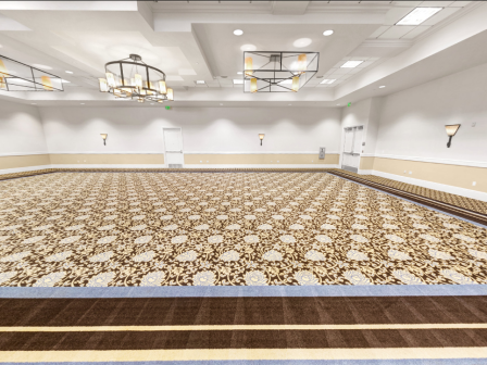 A large empty conference room with patterned carpet, beige walls, and bright ceiling lights, ready for a banquet or meeting.