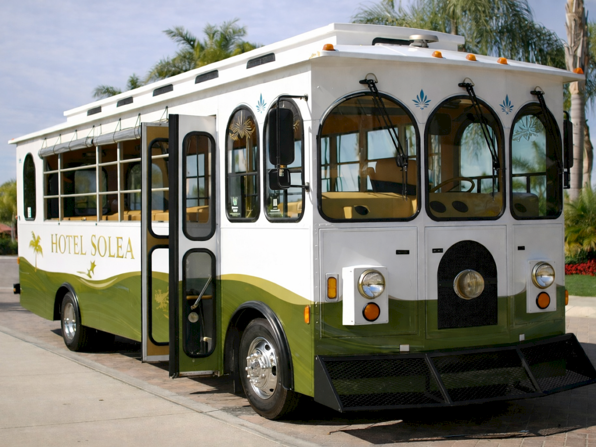 A vintage-style shuttle bus named &ldquo;Hotel Solea&rdquo; parked on a driveway at a sunny location.