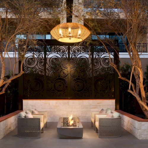 A dimly lit restaurant with neon signs, rustic wooden decor, a central long table, and hanging lanterns creating a cozy, intimate vibe.