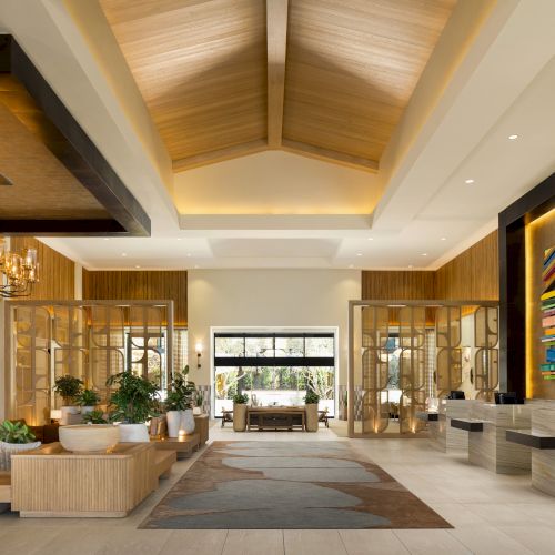 A luxurious hotel lobby with high ceilings, elegant chandeliers, marble floors, and comfortable seating along with warm lighting.