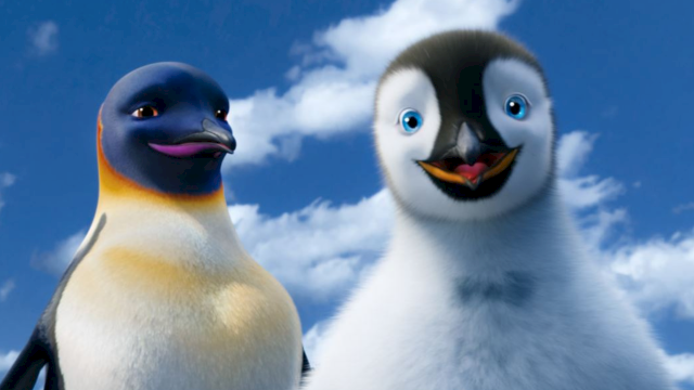 Two cheerful penguins stand close together against a blue sky, smiling at the camera.