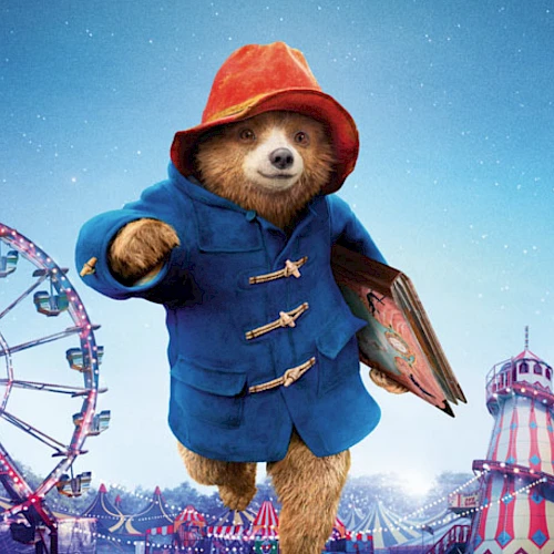 A sloth in a blue coat and red hat is holding a book, standing in a colorful amusement park with a ferris wheel and rides at night.